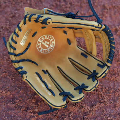 Tan baseball glove with black laces, resting on a dirt baseball field. The brand name "Yardley" is prominently displayed in black lettering.