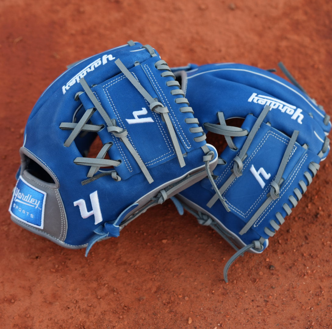 Yardley Blue and Gray baseball gloves laying on top of baseball field clay