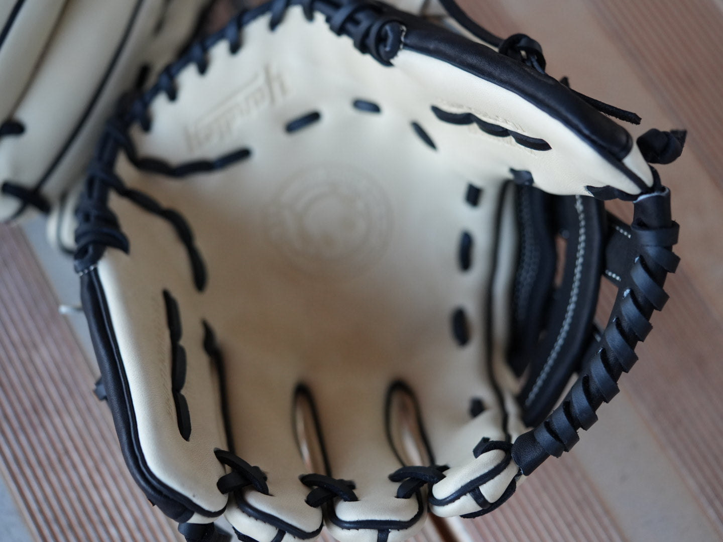 Beige baseball glove with black stitching and red "Yardley" branding, placed on a metal surface. The glove showcases a sleek design with fine craftsmanship.