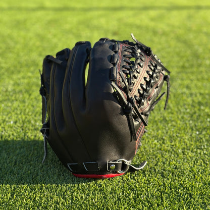 All black with red accent closed back semi-custom baseball glove. The Phantom, set on a turf baseball field