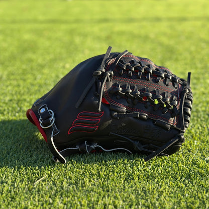 All black with red accent "Phantom" semi-custom glove laying on its side on turf grass