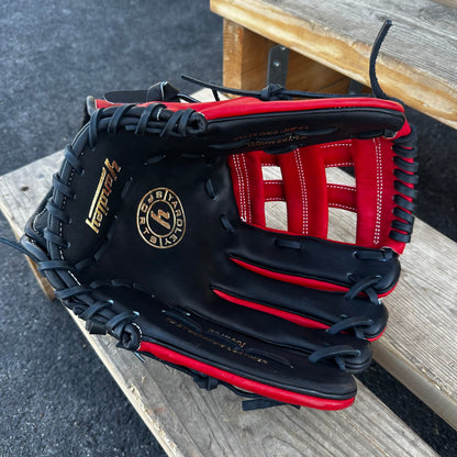  A red Yardley baseball glove with black and white stitching and black laces on a wooden bench. The glove has a "Y" logo on the thumb area, showcasing its unique design. The webbing is an H-web style