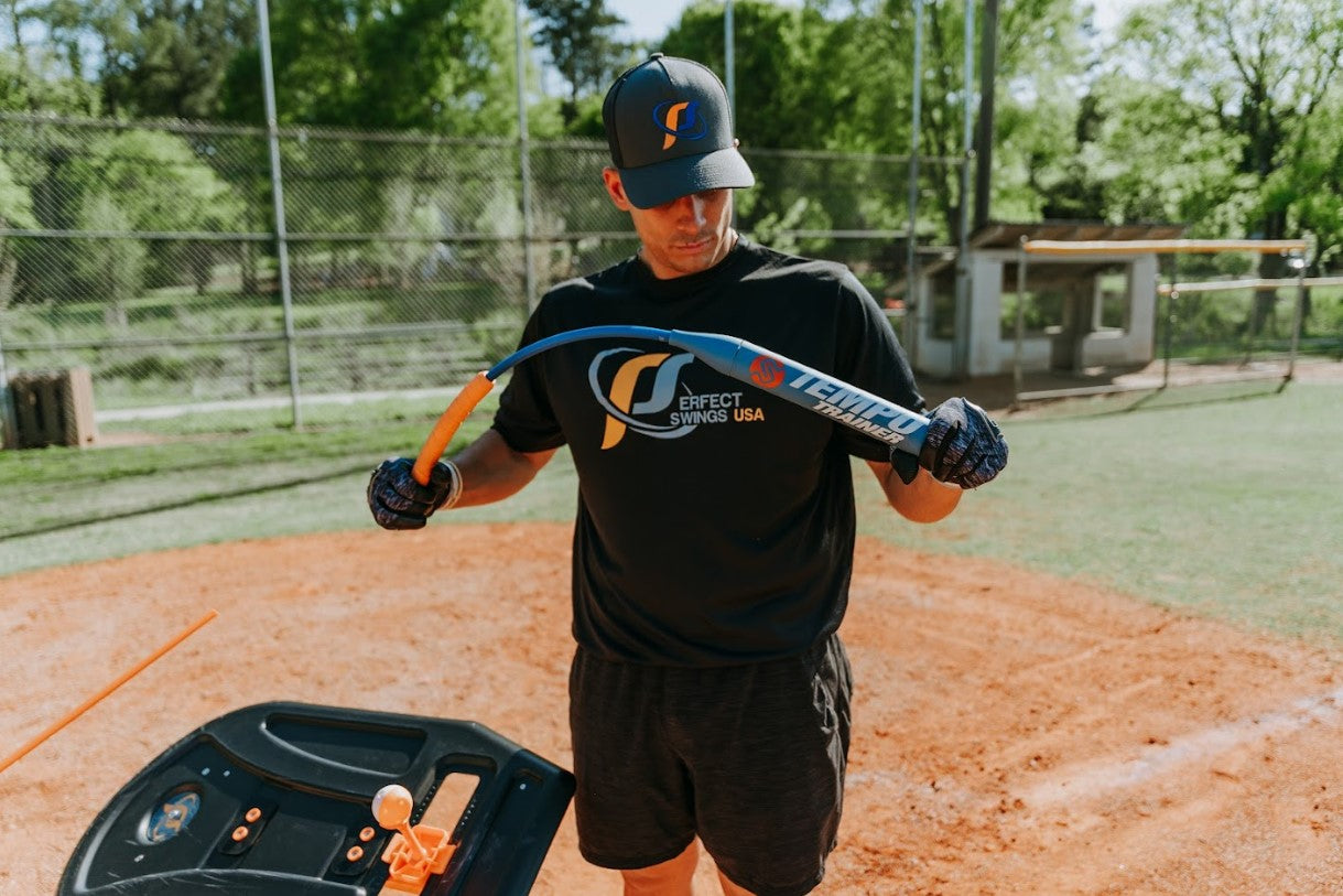 A baseball batter wearing Perfect Swings USA apparel flexing the Tempo Trainer, showing its durability